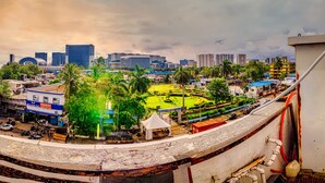 A cityscape with a large green park, modern buildings, and a clear sky. - LA Hotel Metro (Mumbai)