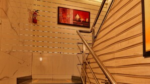 A marble staircase with metal railings, a wooden wall panel, and a framed picture on the wall. - LA Hotel Metro (Mumbai)