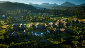 A resort with multiple bungalow-style buildings, a central pool area, and terraced fields in the background. - Sanak Retreat Bali (Gobleg)