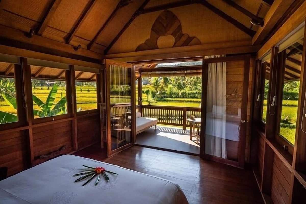 A room with a bed, a window, and a view of a garden.