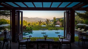 An infinity pool with a view of a lush garden and mountains. - Sanak Retreat Bali (Gobleg)