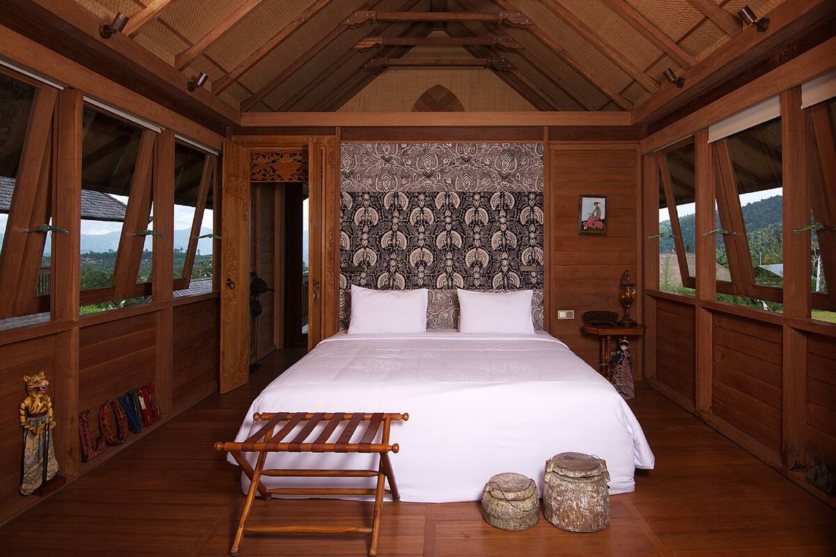 A spacious bedroom with a large bed, wooden walls, and a view of the outdoors.