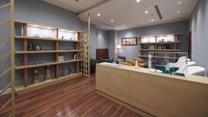 Zona de recepción con estanterías de madera, mostrador y asientos.