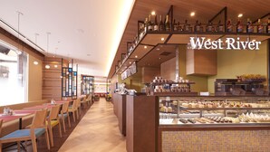 Un restaurante con una barra larga, varias zonas de estar y una vitrina con distintos alimentos.