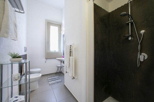 Et moderne badeværelse med en glasvæg omkring brusenichen, toilet og vask.