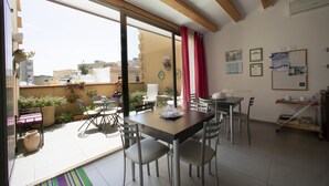 A dining area with a table and chairs, a sliding glass door leading to a balcony, and a view of the cityscape. - Bed & Breakfast Terrazze Villanova (Trapani)