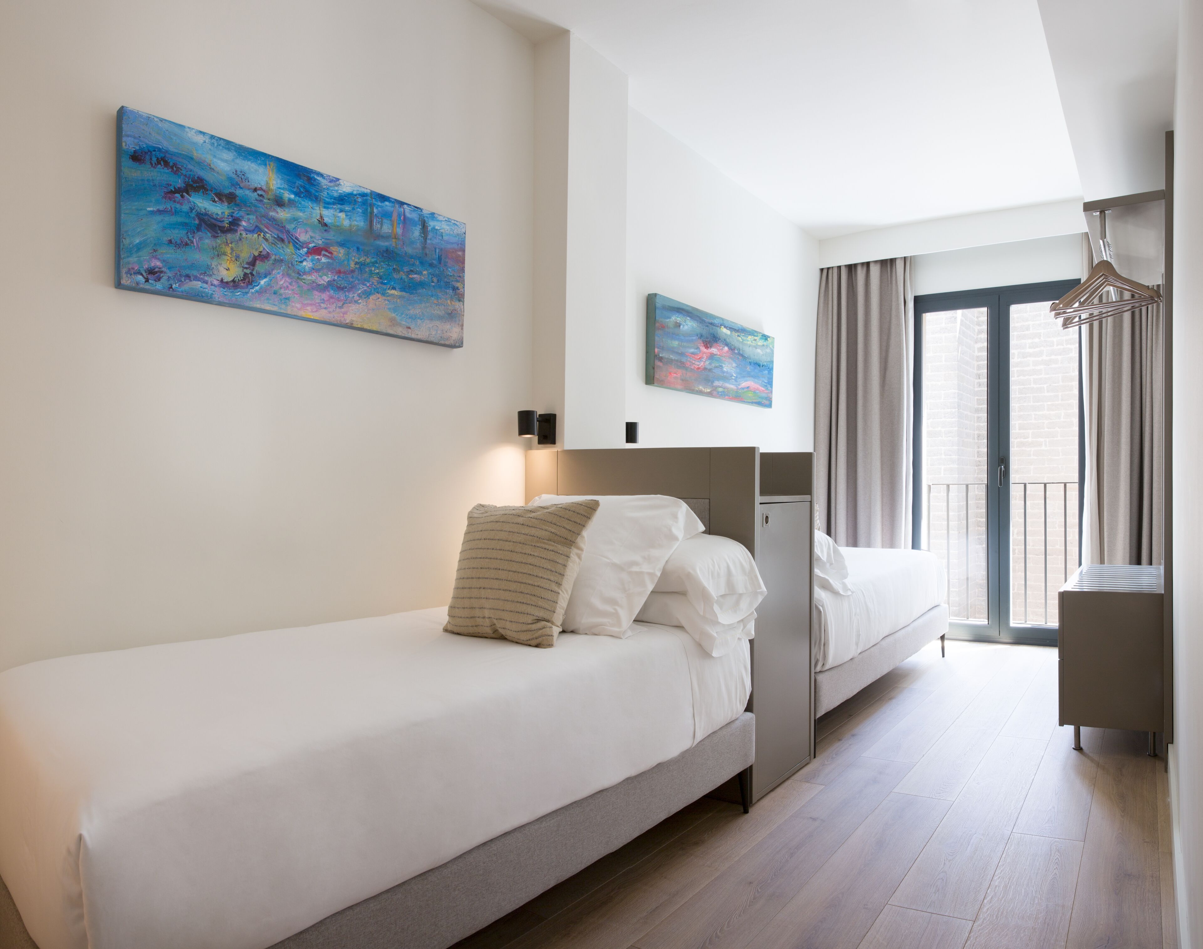 Habitación de hotel moderna con una cama grande, un escritorio y un balcón con cortinas.