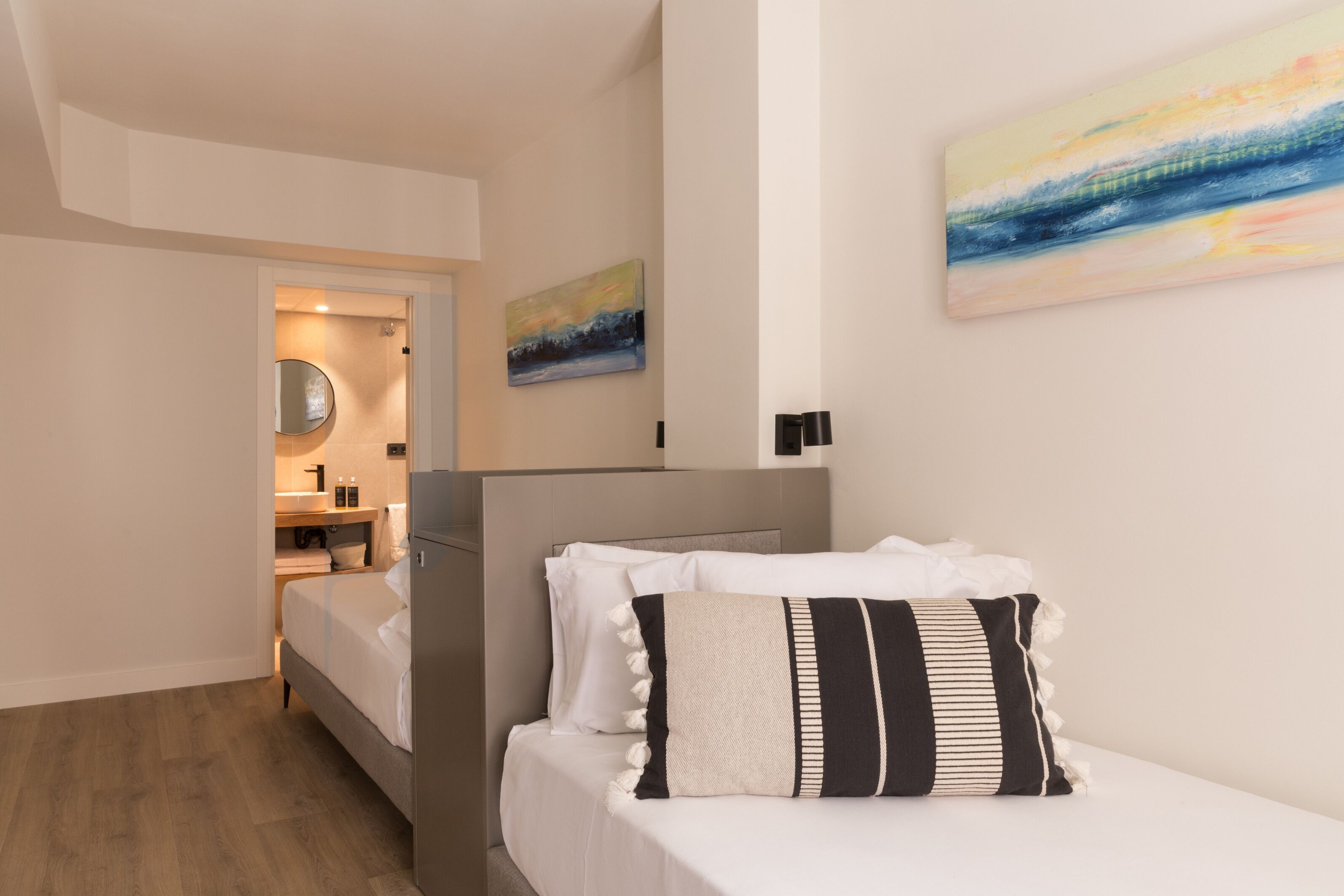 Un dormitorio moderno con cama, mesita de noche, espejo y un cuadro en la pared.