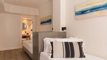 Quarto moderno com uma cama, mesa de cabeceira, espelho e um quadro na parede.