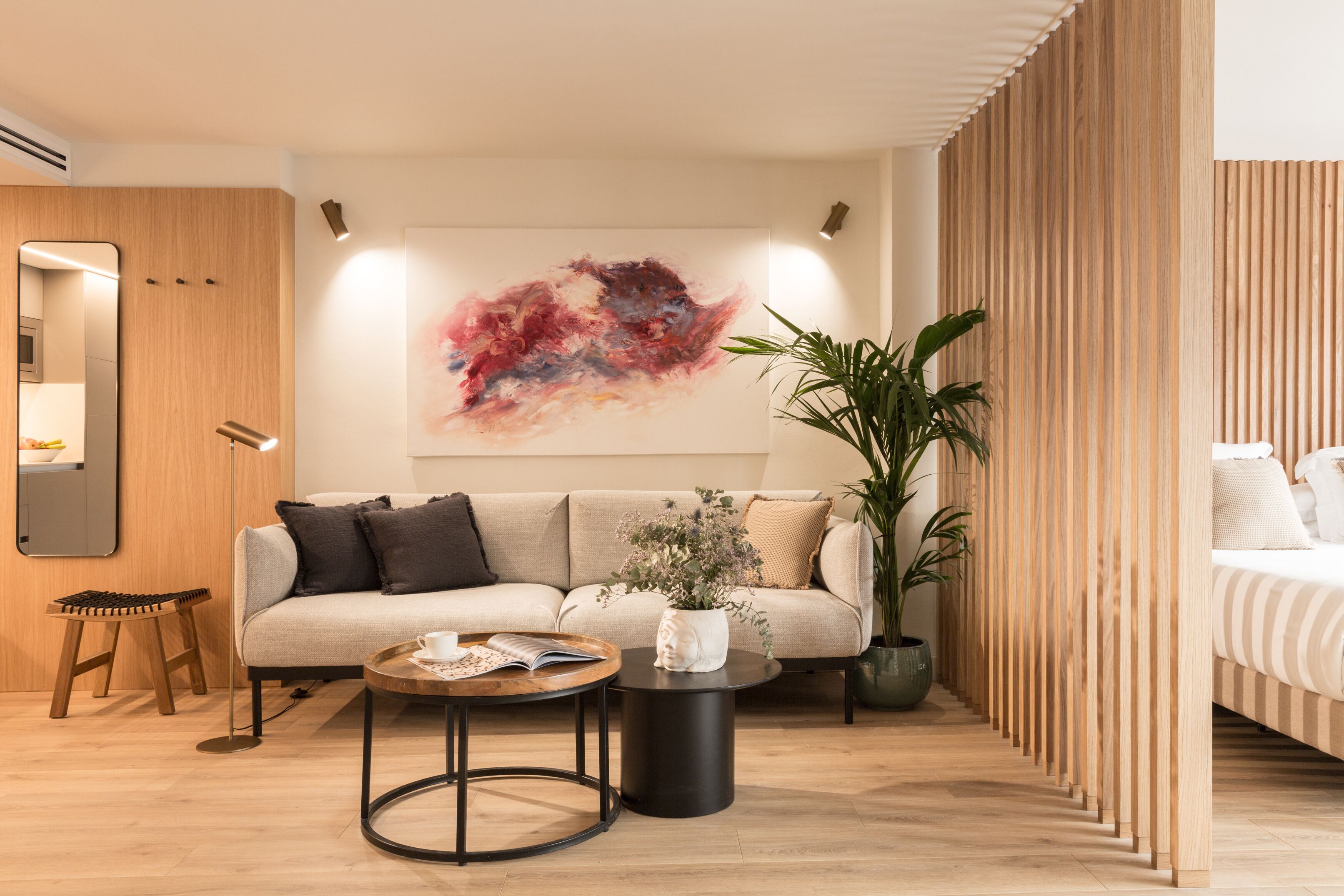 A modern living room with a sofa, coffee table, and a large abstract painting on the wall.
