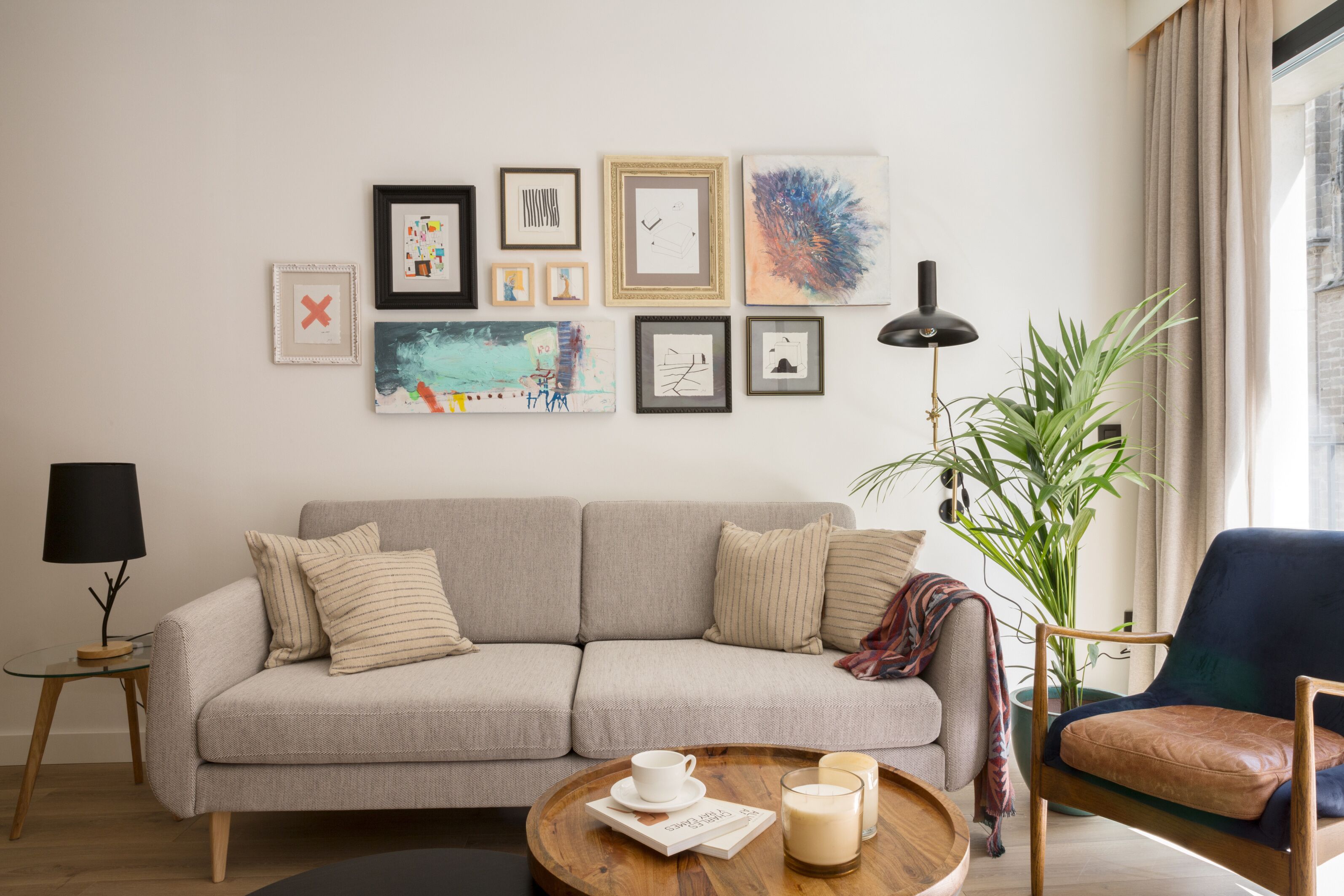 Una sala de estar con sofá, sillones, una mesita de centro y una pared decorada con cuadros.