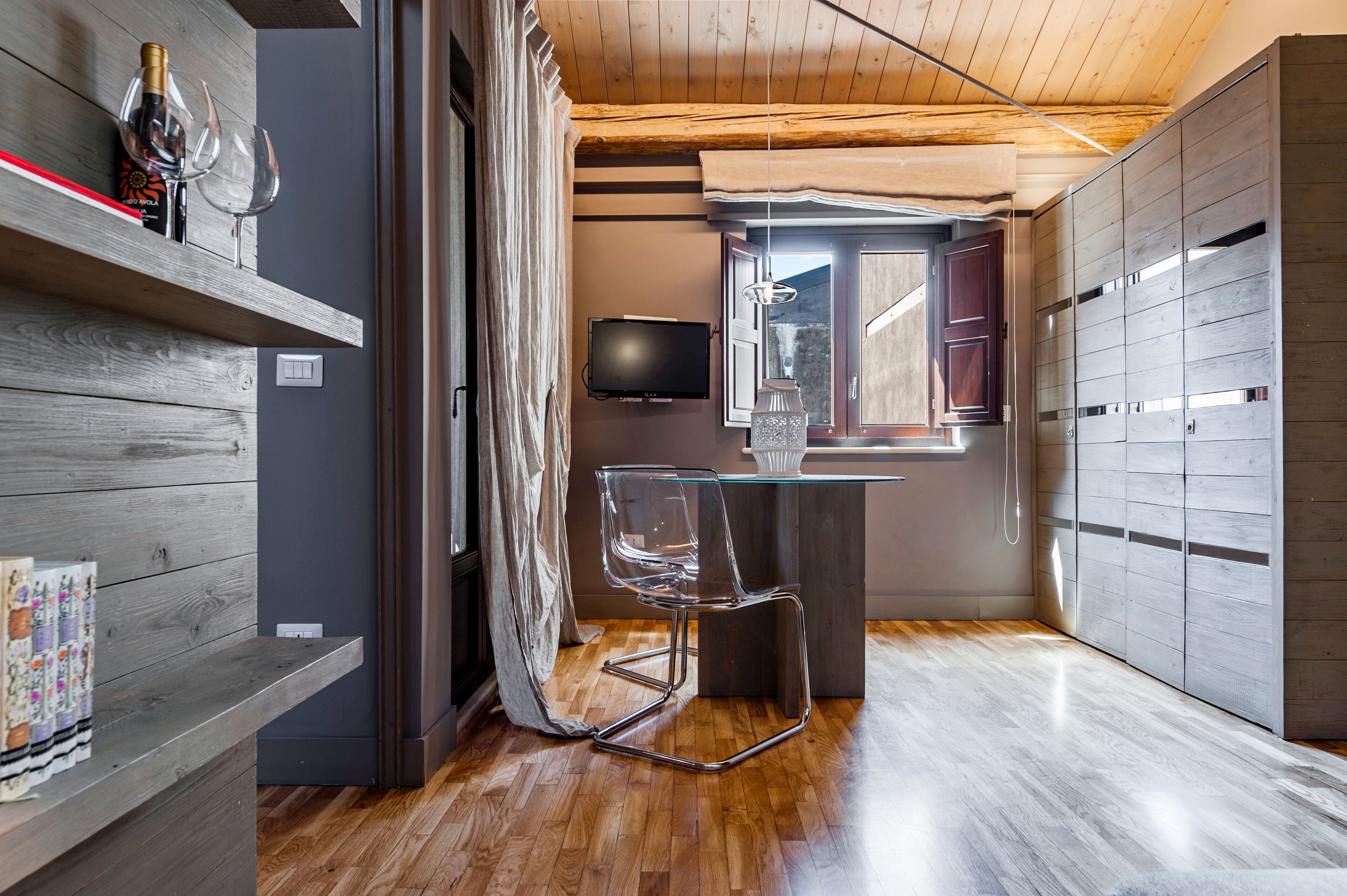 Een moderne keuken met houten kastjes, een glazen tafel en een transparante stoel.