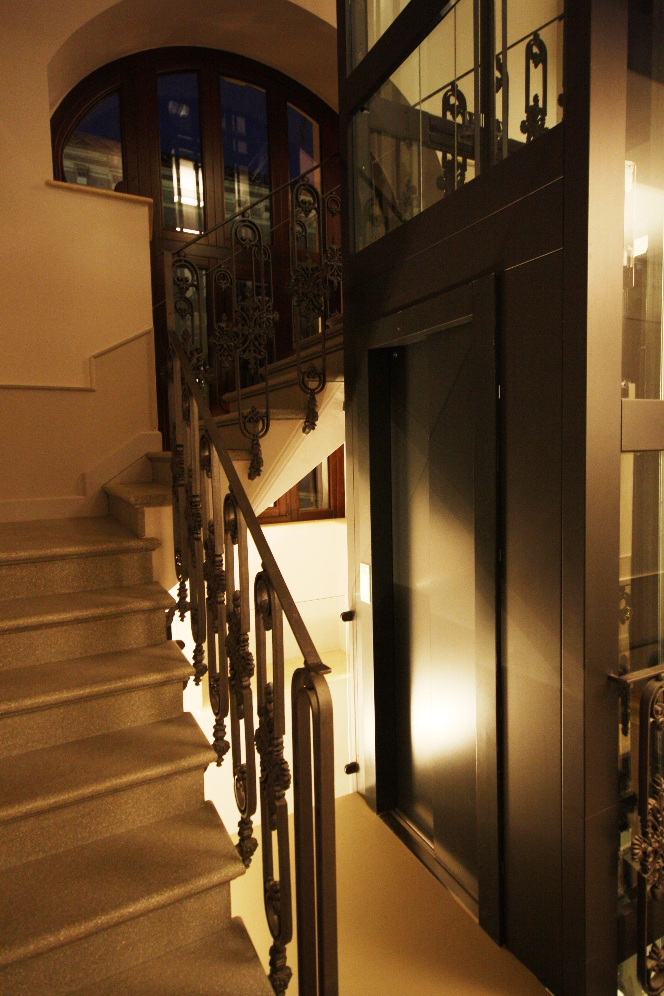 Uma escadaria com grades de metal elaboradas e uma porta escura.
