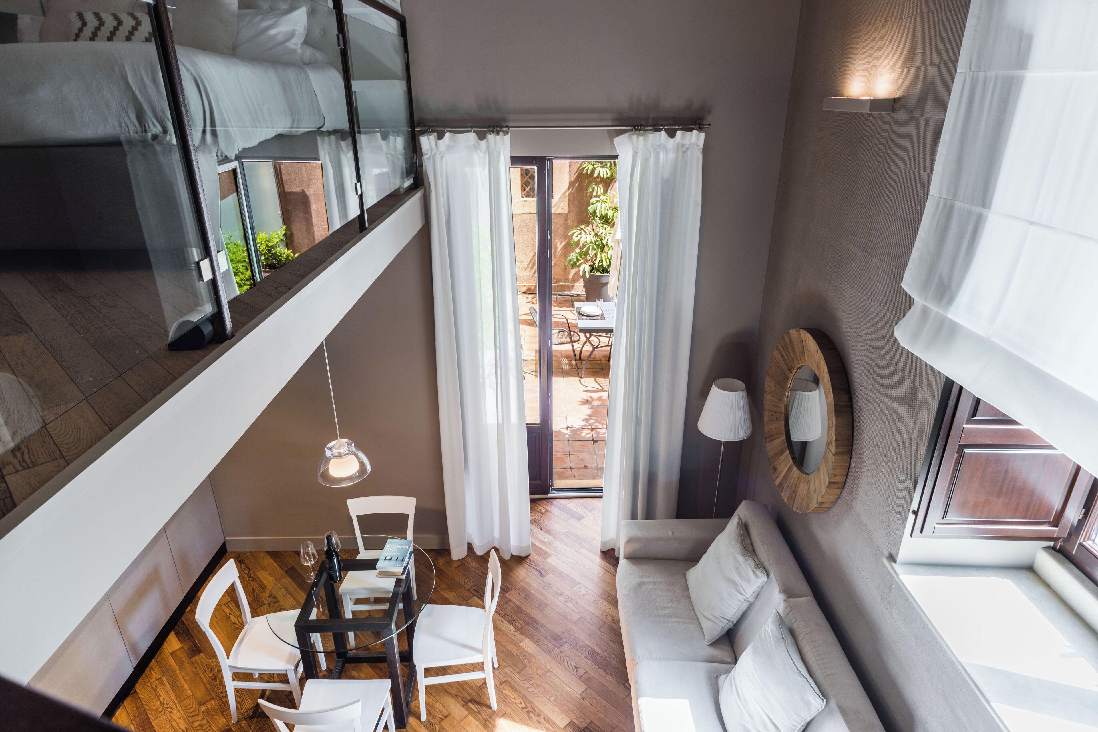 A modern interior with a dining area, a sofa, and a view of the outside.