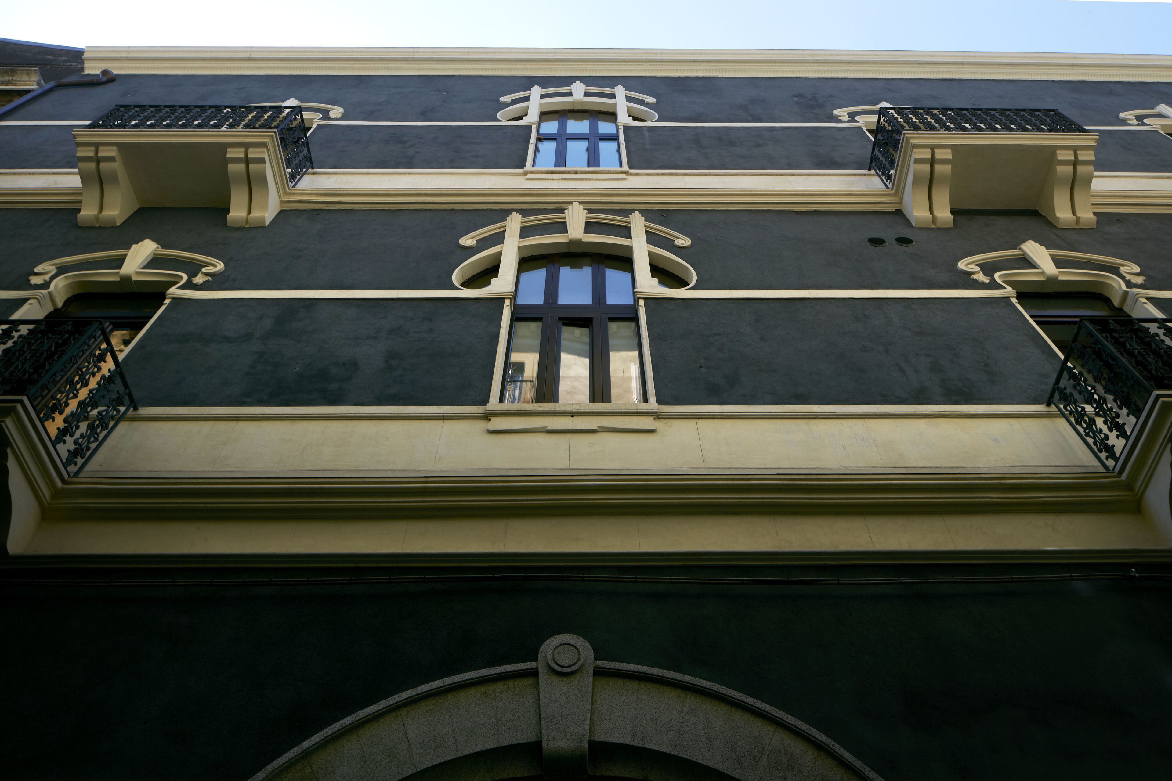 A building facade with three windows, each with a distinct design.