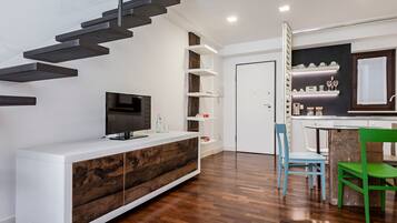 A modern kitchen with white cabinetry, a built-in stove, and a dining area with two chairs.