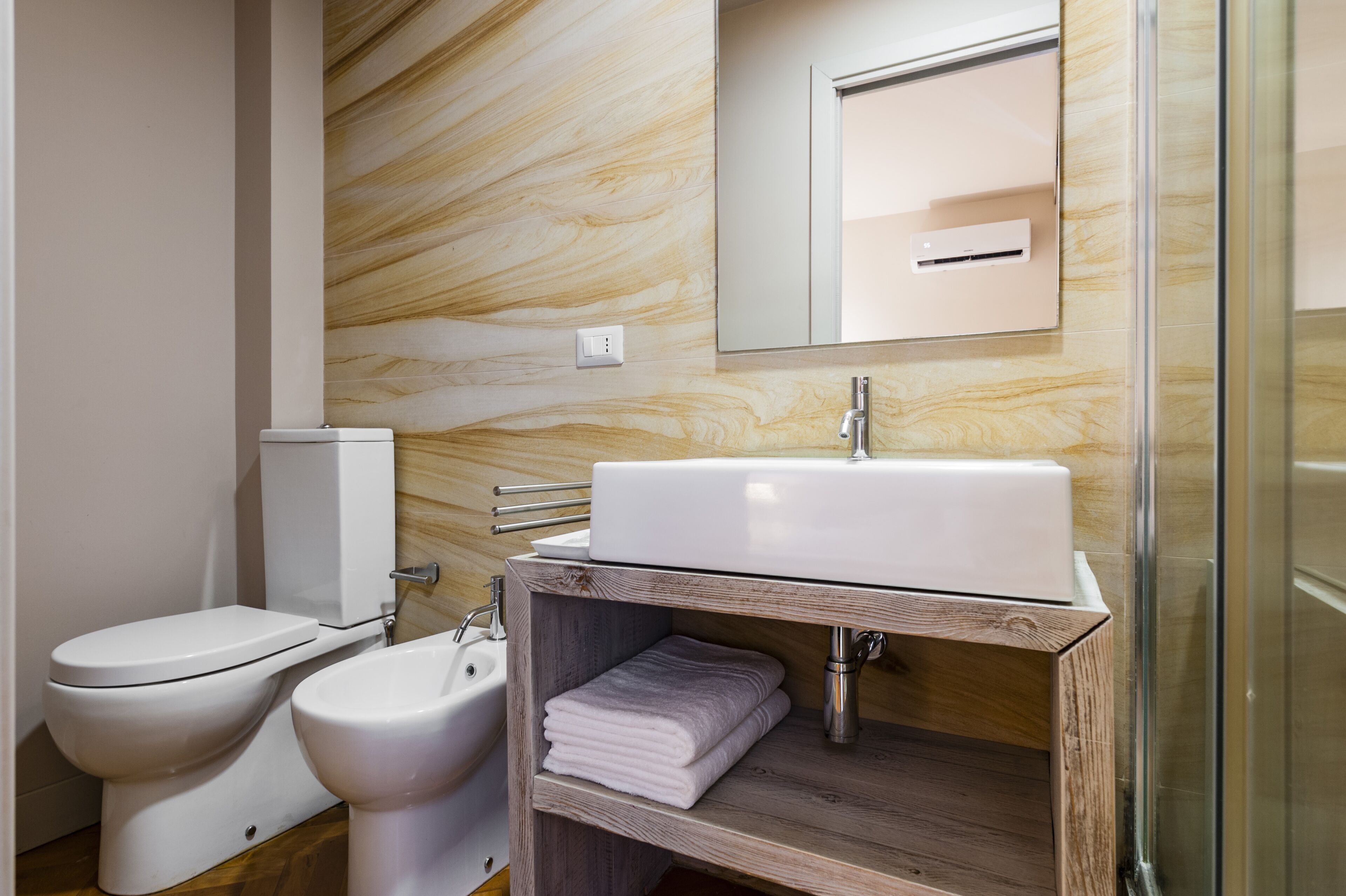 A modern bathroom with a white sink, toilet, and bidet.