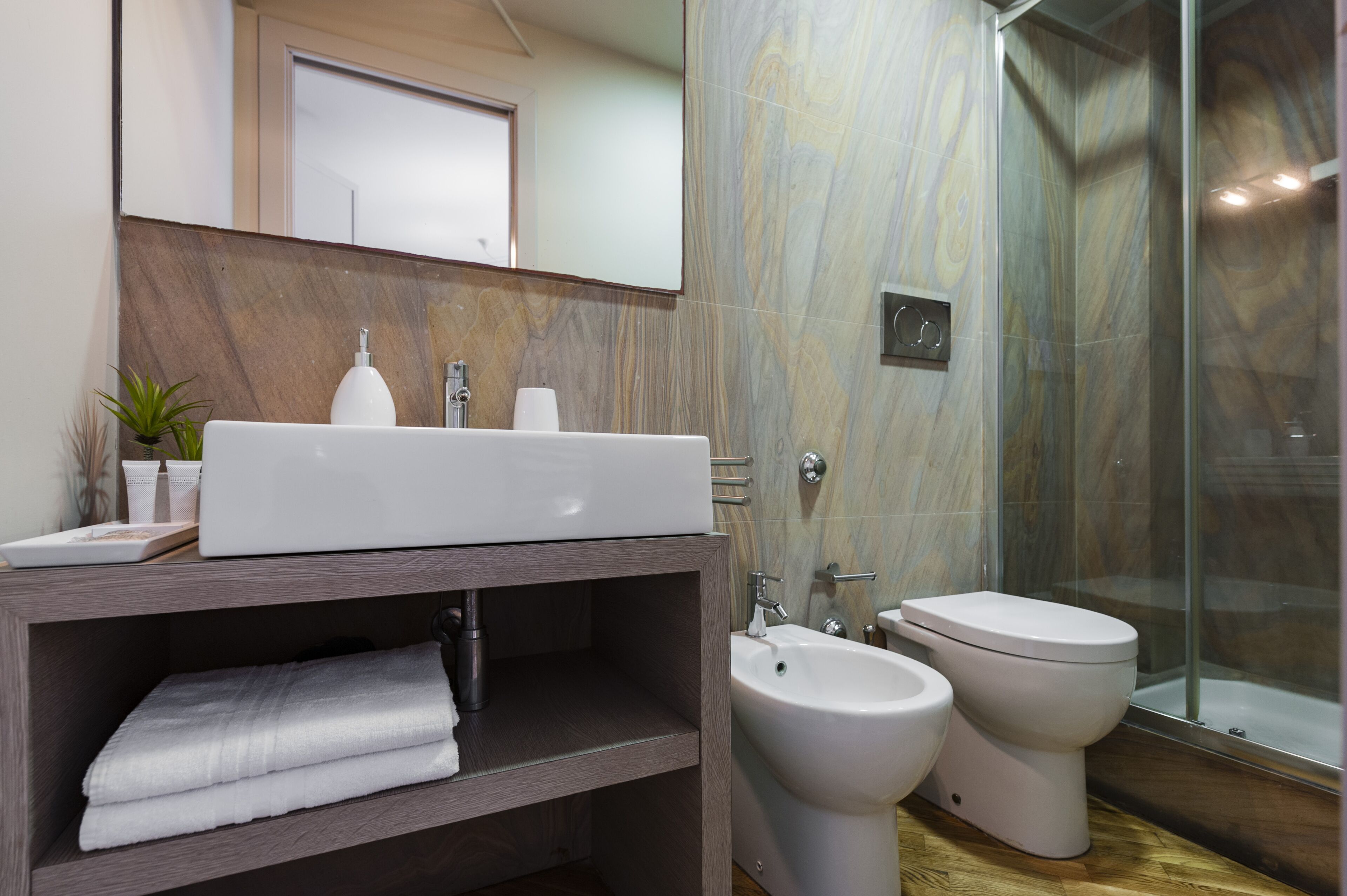 A modern bathroom with a large sink, bidet, and shower.