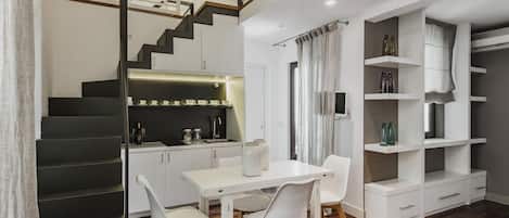 Una cocina moderna con comedor, escalera y estanterías empotradas.