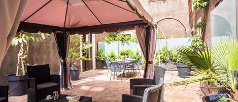 An outdoor patio area with wicker furniture, a table with a book, and potted plants.