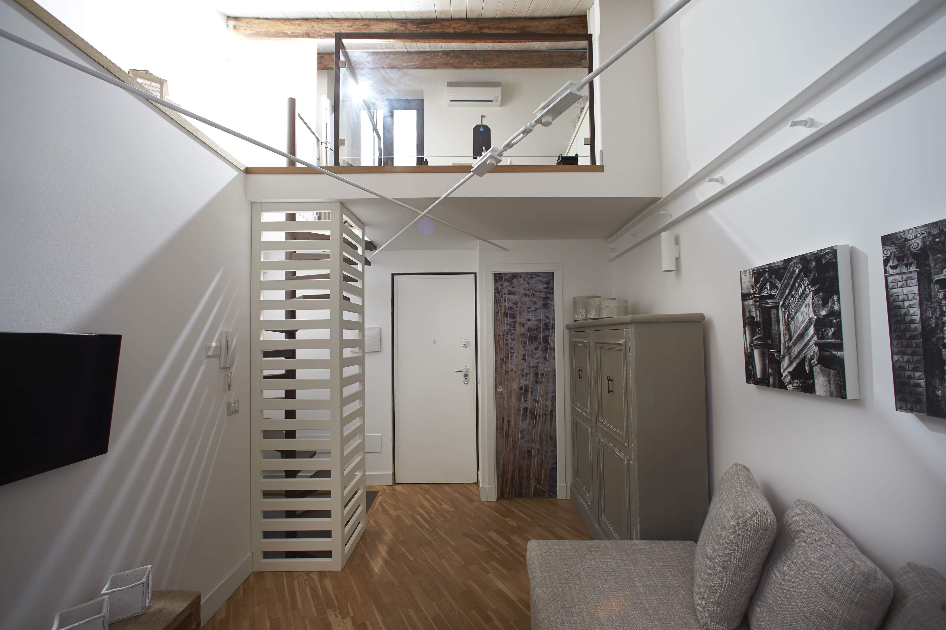 Un intérieur moderne avec un plancher en bois, un canapé, un téléviseur et un escalier menant à un niveau supérieur.