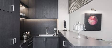 A modern kitchen with dark cabinetry, a stainless steel sink, and a countertop with a glass container.