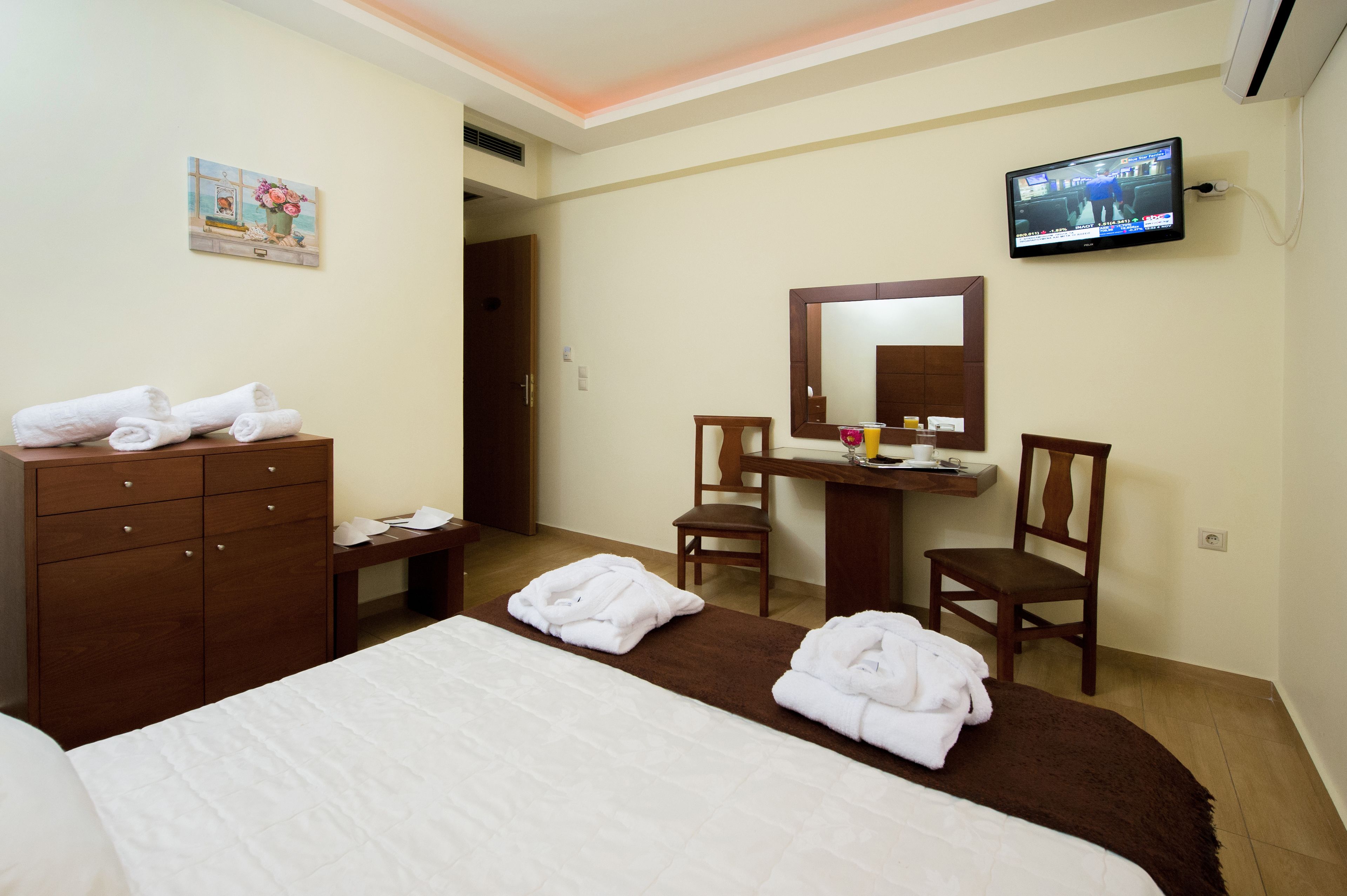 A hotel room with a bed, a desk, a chair, a TV, and a wardrobe.