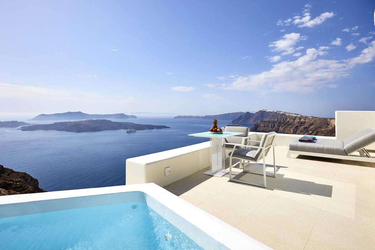 Terraza en la azotea con piscina, sillones de descanso y una mesa con fruta.