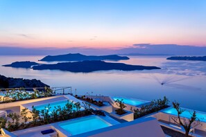 Un resort con varias piscinas, vistas al mar y islas a lo lejos.