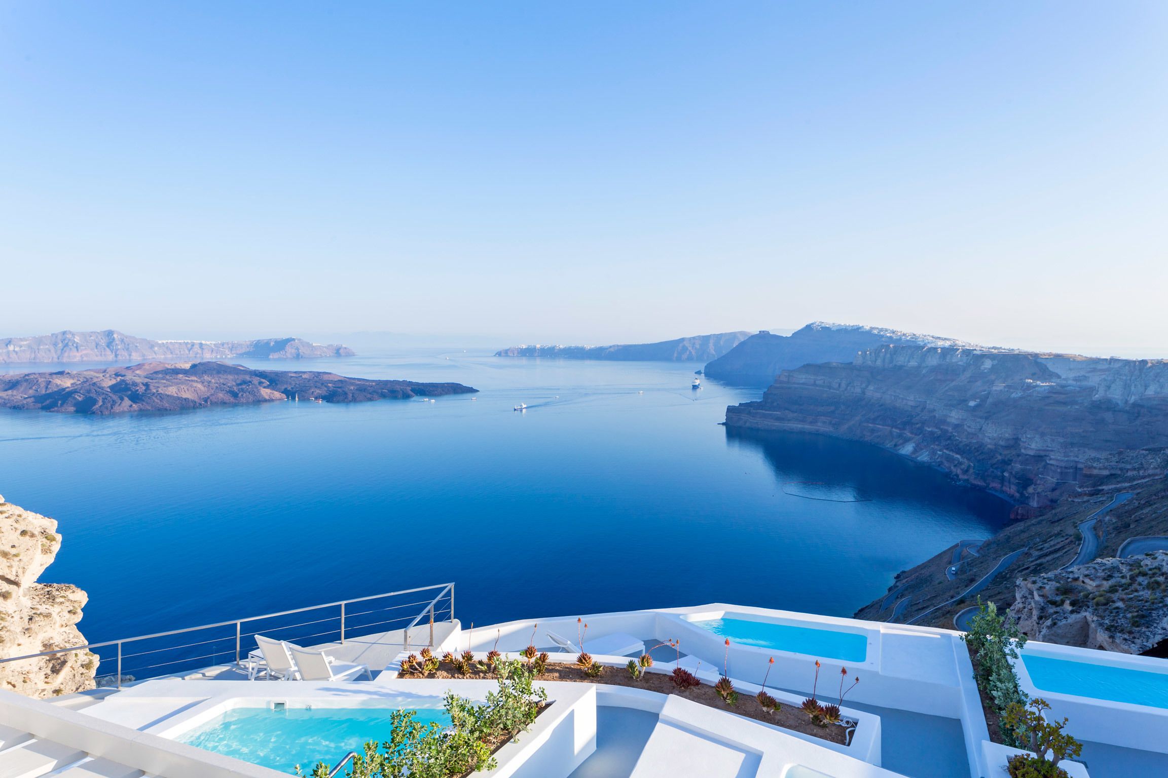 Vista a la piscina con vistas a una gran masa de agua, acantilados, cielo despejado y una isla distante.