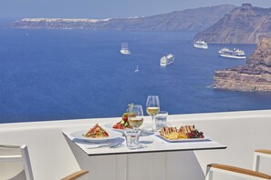 Una mesa con comida y bebidas, con vistas al mar, cruceros y acantilados.
