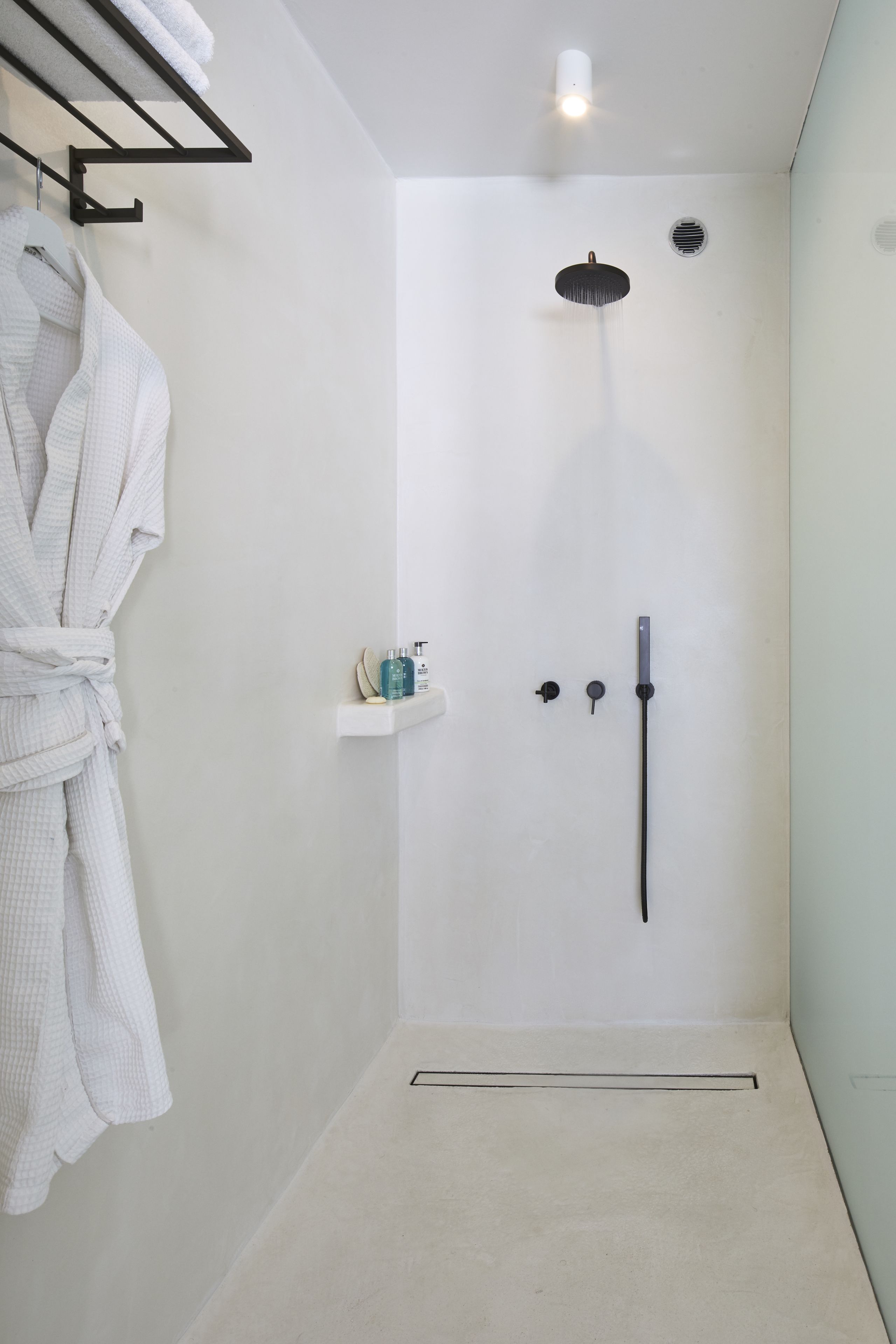 Ein modernes Badezimmer mit barrierefreier Dusche, Handtuchhalter und einer kleinen Ablage für Toilettenartikel.