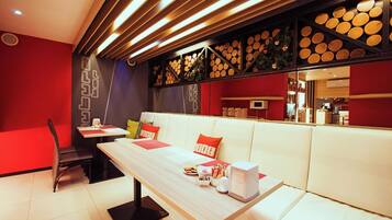 Un interior moderno con una larga mesa de madera, asientos blancos acolchados y una pared decorada con troncos de madera circulares.