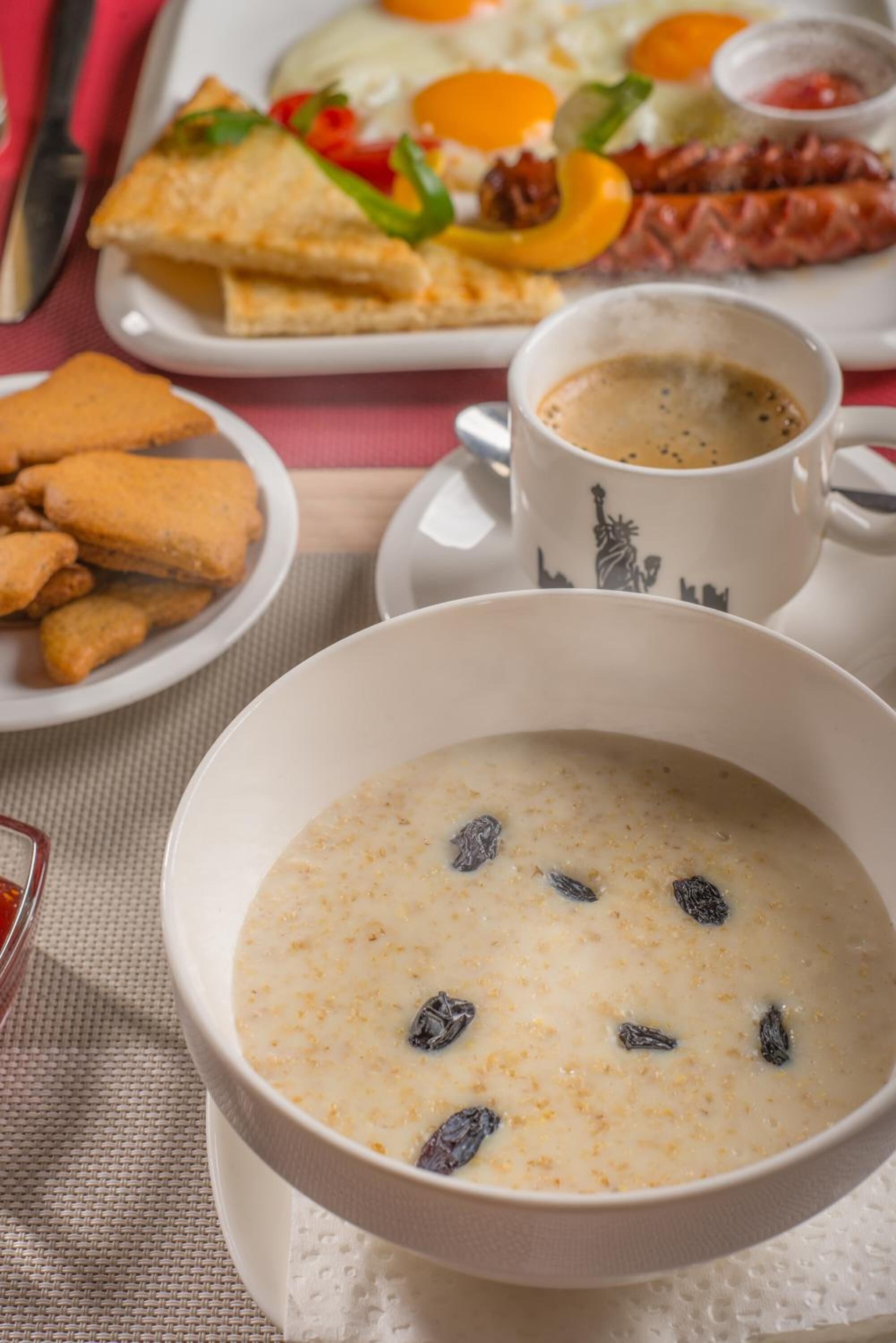 A breakfast setting with a bowl of oatmeal, toast, sausages, and a cup of coffee.