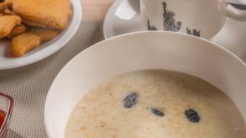 A breakfast setting with a bowl of oatmeal, toast, sausages, and a cup of coffee.