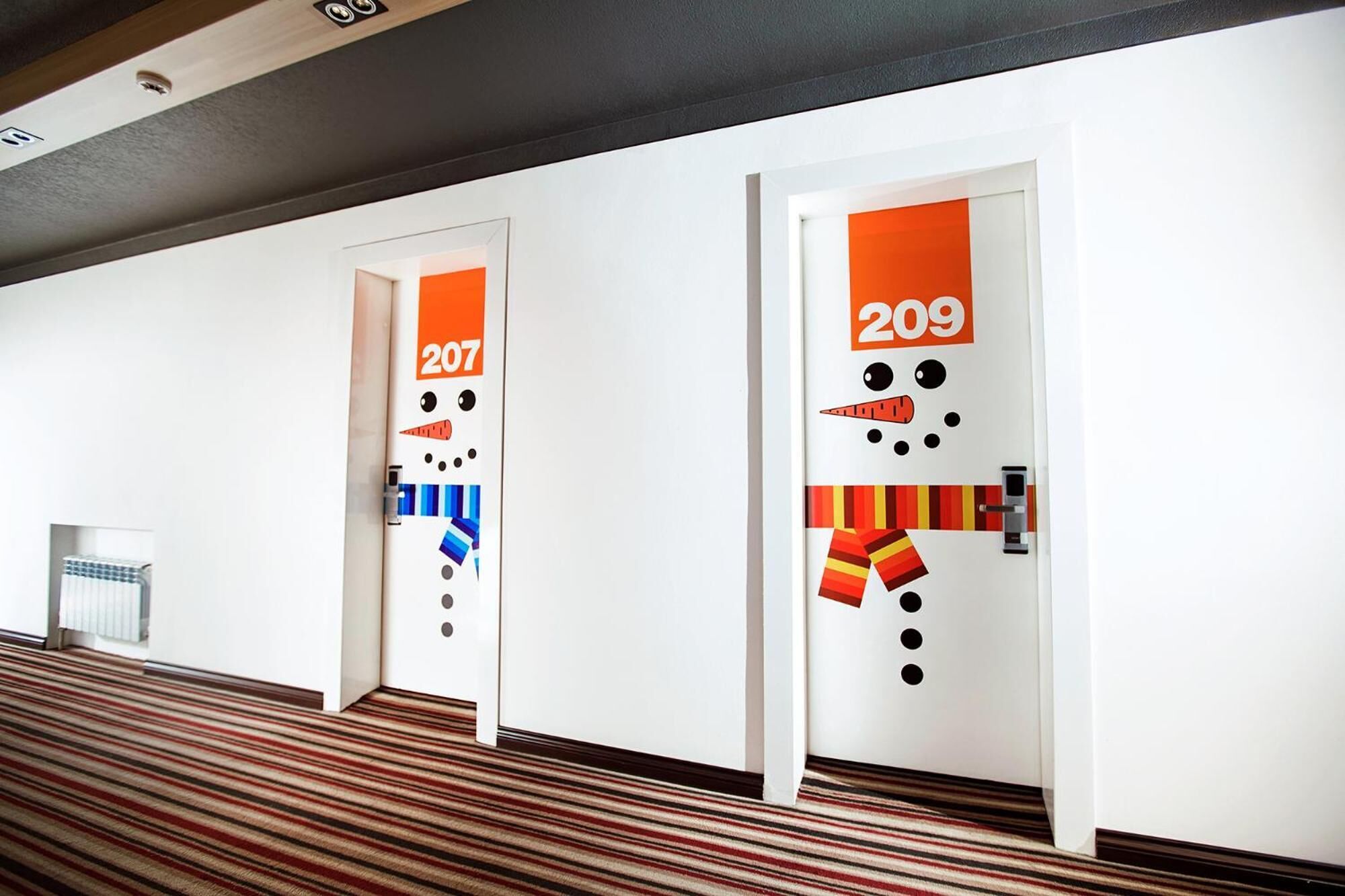A hotel corridor with doors numbered 207 and 209, featuring playful snowman designs.