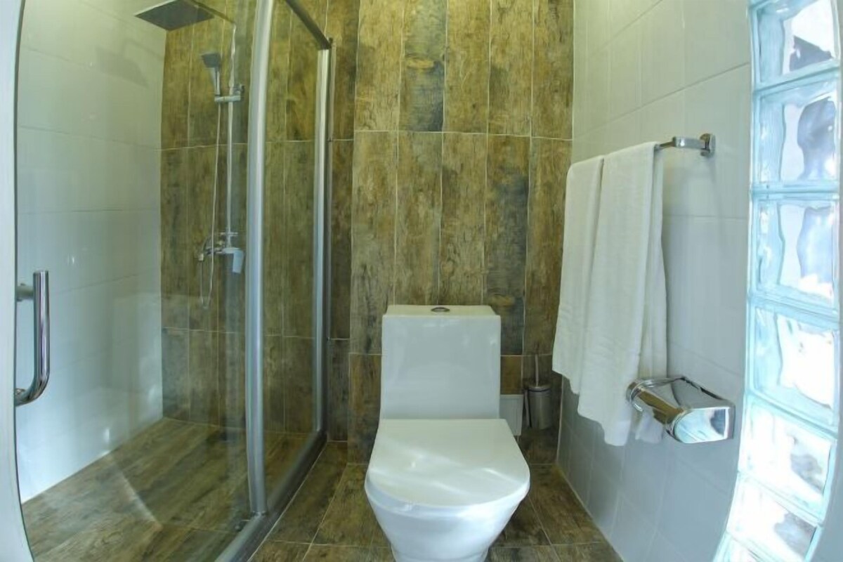 Un baño con ducha de vidrio, inodoro y perchero para toallas.