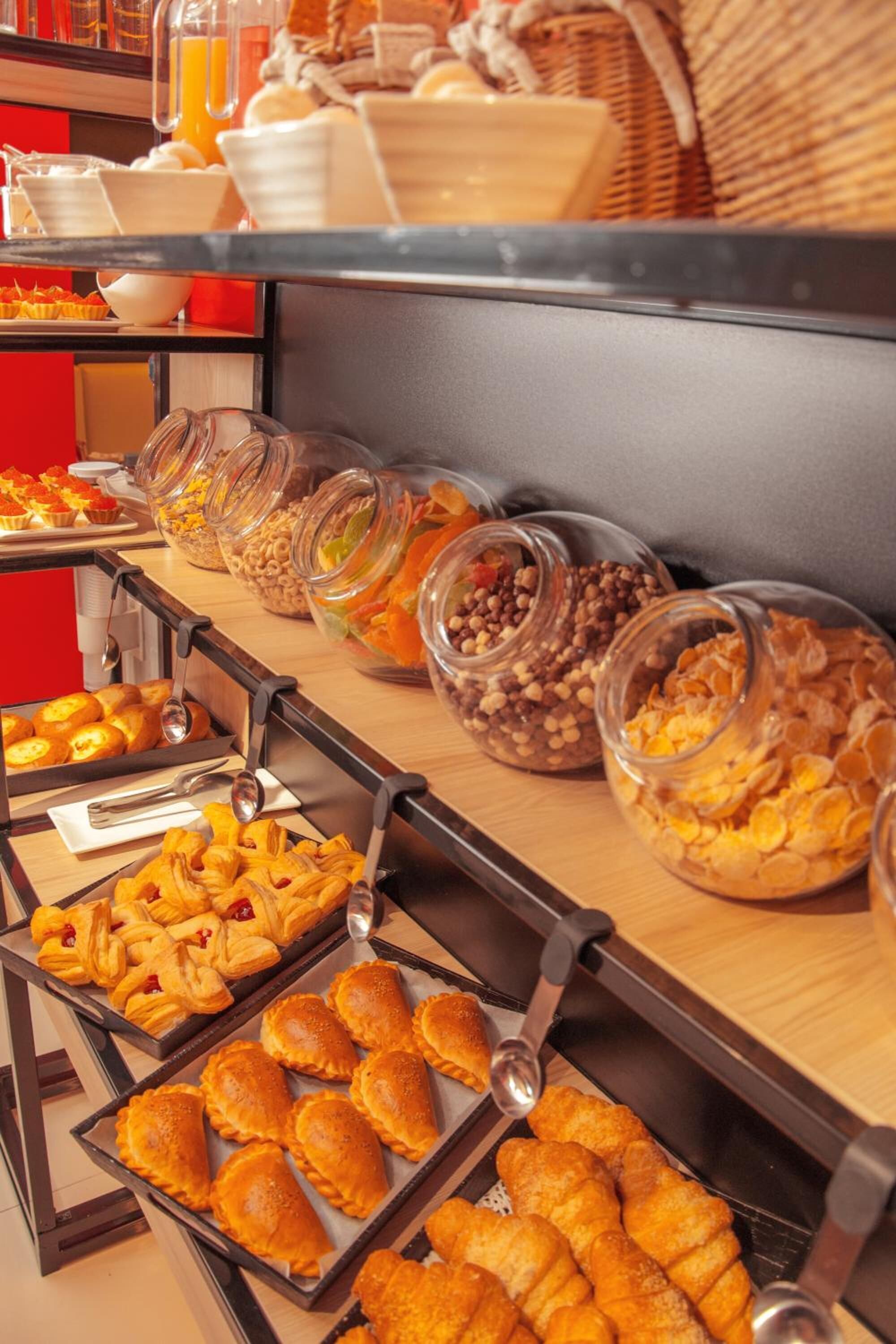 A buffet with various food items including pastries, cereals, and fruits.