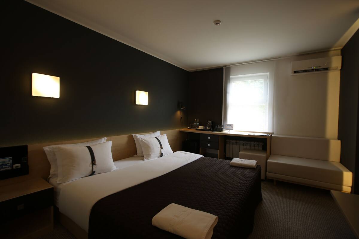 Een hotelkamer met een groot bed, een bureau, een stoel en een raam.