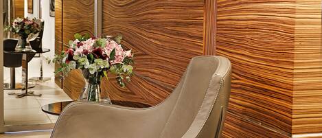Un interior moderno con un sillón de cuero, panel de madera, cuadros enmarcados y un florero con flores.