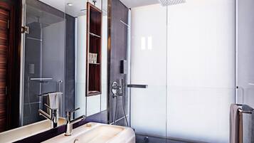 Een moderne badkamer met een grote spiegel, een wastafel, een douche en een douchecabine met glazen wanden.