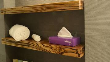 Een badkamer met houten planken waarop handdoeken, toiletartikelen en een zakdoos liggen.