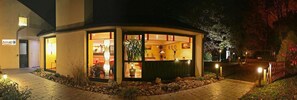 A small, well-lit building with a reception area, surrounded by a landscaped garden with rocks and plants. - Contact Hotel du Parc (Orvault)