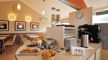 Zona de esmorzar amb barra de buffet, incloent pa, pastissos i una estació de cafè.