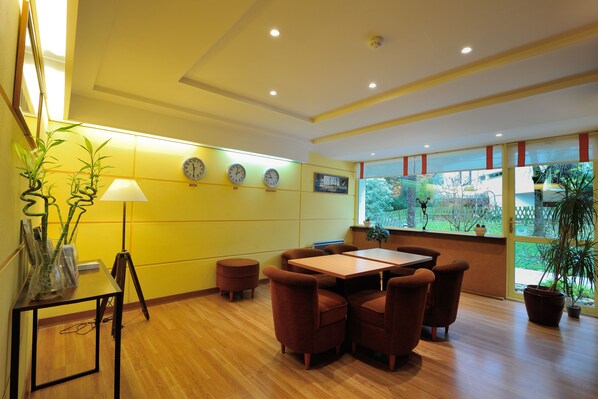 A dining area with a wooden table and brown chairs, a lamp, and a potted plant.