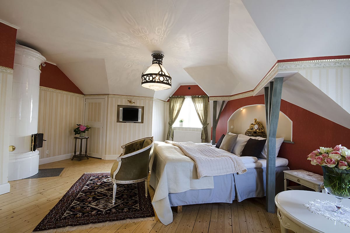 Un dormitorio con cama, una silla, una mesa y una lámpara decorativa.