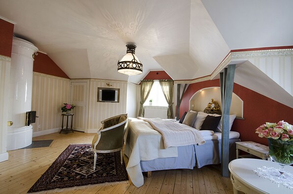 A bedroom with a bed, a chair, a table, and a decorative lamp.
