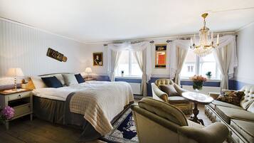 A well-appointed bedroom with a large bed, a sitting area with a table and chairs, and a chandelier.