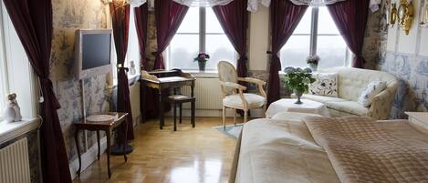 Quarto de hotel com cama, escrivaninha, cadeira e sofá.