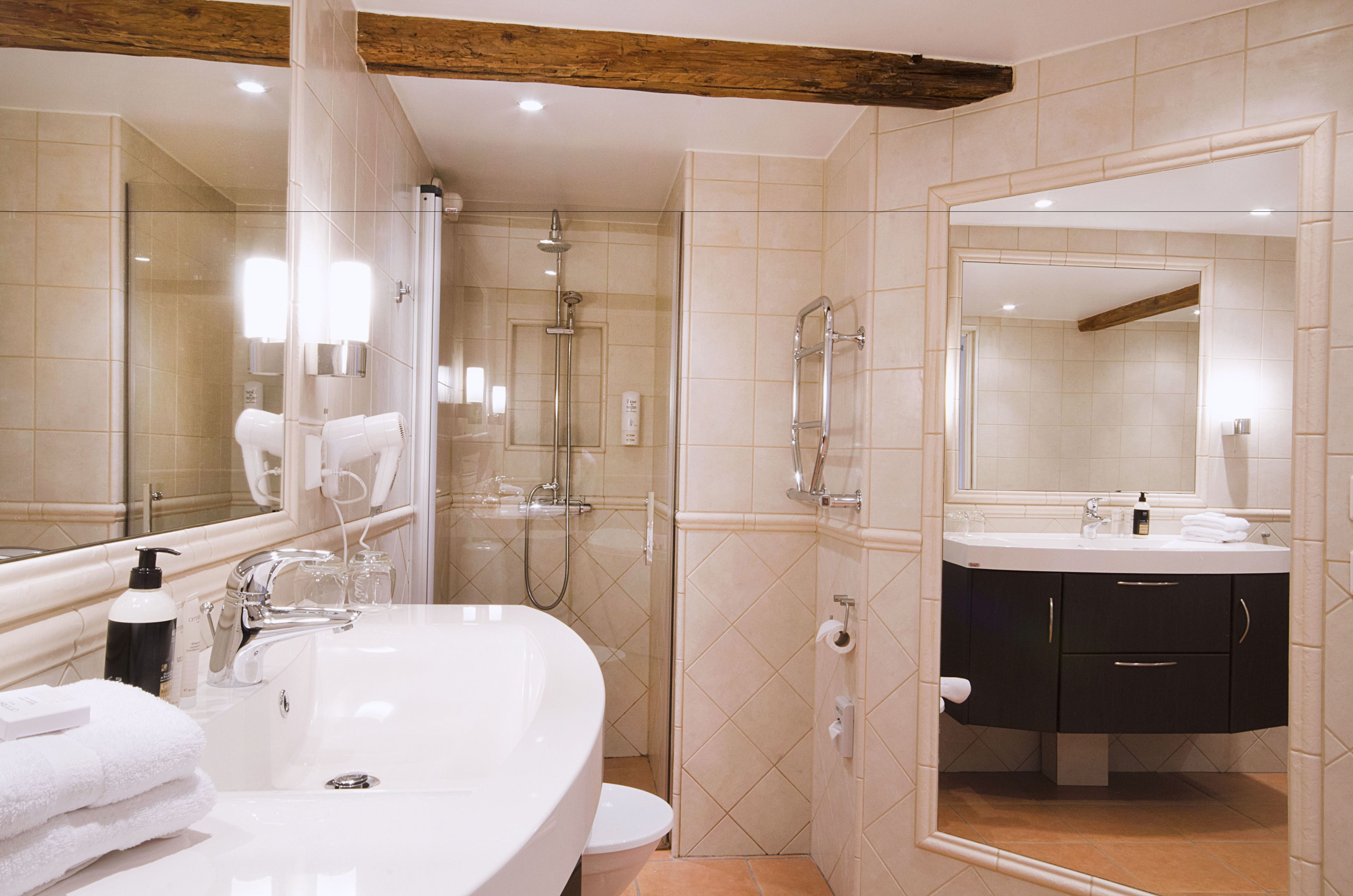 Un baño moderno con un espejo grande, una bañera, una ducha y un lavabo con tocador.